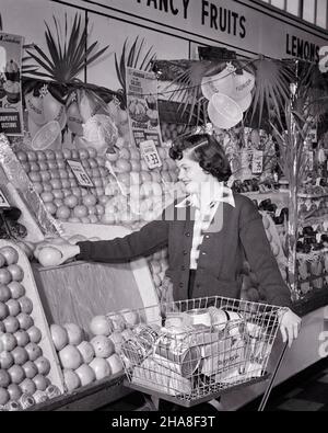 1950S TEENAGER-MÄDCHEN SCHIEBEN EINEN LEBENSMITTELKARREN AUSWAHL EINER GRAPEFRUIT IN DER PRODUKTION ABSCHNITT EINES SUPERMARKTS - S4984 LAN001 HARS KOPIEREN RAUM HALBE LÄNGE PERSONEN GESCHÄFTE TEENAGER MÄDCHEN B&W SHOPPER BRÜNETTE KÄUFER GLÜCK FRÖHLICH WAHL ERNÄHRUNG GELEGENHEIT LÄCHELT SPEICHERT FRÖHLICH PRODUZIEREN TEENAGED COMMERCE JUGENDLICHE SCHWARZ-WEISSE UNTERNEHMEN KAUKASISCHEN ETHNIZITÄT WAHL ZITRUS ALTMODISCHEN ABSCHNITT AUSWAHL Stockfoto