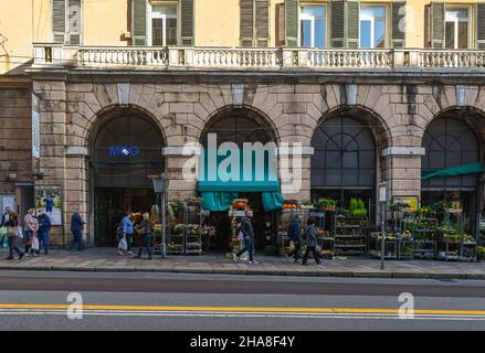 Außenansicht des Orientalischen Marktes in der Via XX Settembre, einer der Hauptstraßen von Genua, mit den Pflanzen eines Blumenladens auf dem Bürgersteig, Italien Stockfoto