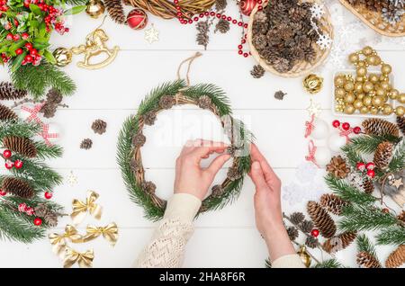 Schritt für Schritt einen kleinen Weihnachtskranz machen, Schritt 4 - kleine Tannenzapfen auf die Basis kleben Stockfoto