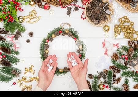 Schritt für Schritt einen kleinen Weihnachtskranz machen, Schritt 9 - Nehmen Sie weiße Plastikschneeflocken Stockfoto