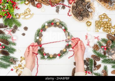 Einen kleinen Weihnachtskranz Schritt für Schritt machen, Schritt 11 - Nehmen Sie die rote Perlen Dekoration Stockfoto