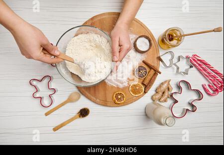 Frauenhände mischen trockene Zutaten in einer Schüssel mit Mehl, während sie Lebkuchenteig für Weihnachtsplätzchen zubereiten. Essen, Kulinarik, Weihnachten feiern Stockfoto