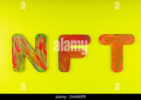Nicht fungibler Token. NFT Akronym für mehrfarbige Buchstaben auf gelbem Hintergrund. Crypto Art Konzept. Speicherplatz kopieren. Draufsicht Stockfoto