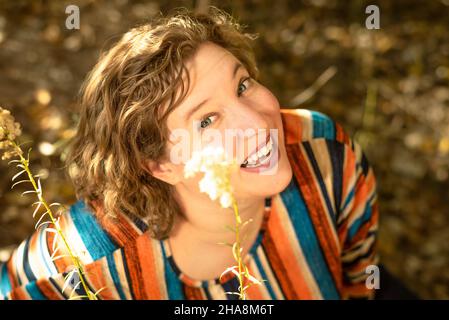 Blonde, blauäugige Frau zwischen Herbstblumen. Stockfoto