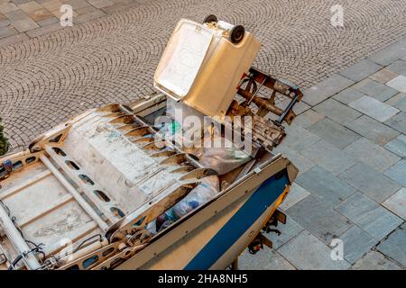 LKW hebt und leert den Behälter für die separate Sammlung von Kunststoff, der recycelt werden soll Stockfoto