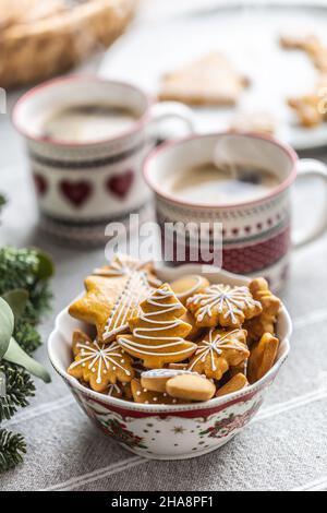 Eine Schüssel voller weihnachtlicher Lebkuchen auf dem Tisch führte zu einem Adventskranz und zwei Tassen mit Kaffee, Punsch oder Tee. Stockfoto