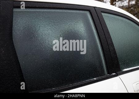 An kalten Wintertagen im Freien bedeckt die Glasscheibe des Autos eine Schicht Eisregen. Konzept für extreme Wetterbedingungen. Stockfoto