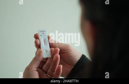 Das Gesicht einer verschwommenen Frau zeigt einen positiven schnellen Covid-19-Test Stockfoto