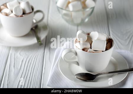Auf einem weißen Holztisch ein Becher mit heißer Schokolade und Marschwalben Stockfoto