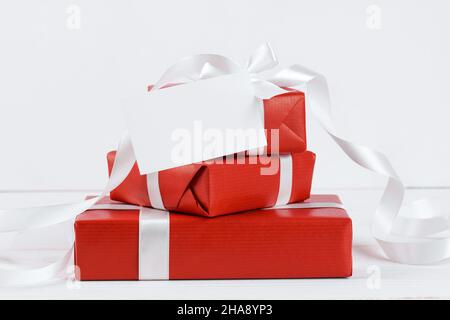 Stapel von roten Bastelgeschenken mit weihnachts-Geschenkkarte Mockup auf weißem Hintergrund. Weihnachten und Neujahr Winter festlichen Hintergrund, Valentinstag Geschenkkarte Stockfoto