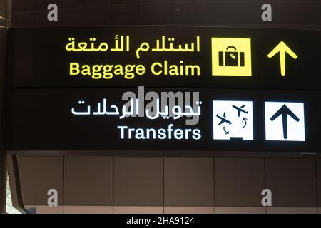 Flugtransfer-Schild und Gepäckausgabe-Schild am Flughafen in englischer und arabischer Sprache Stockfoto