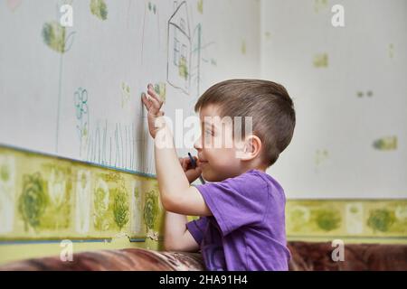 Boy zeichnet an den Wänden. Kind hat Spaß und Flecken an der Wand Stockfoto