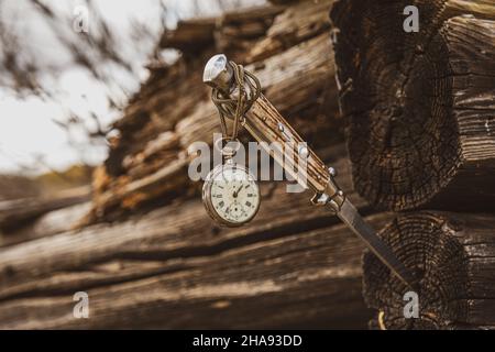 Eine alte Uhr, die an einem Messer hängt, steckt in einer alten Hütte Stockfoto