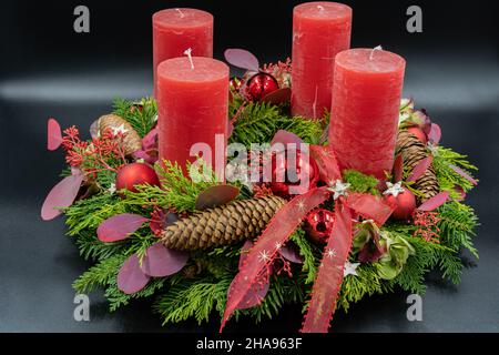 Low-Angle-Ansicht des schönen neuen Adventskranzes mit vier roten Kerzen auf schwarzem Hintergrund. Stockfoto