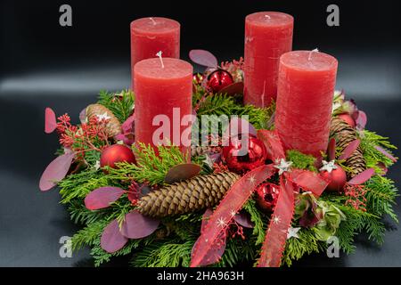 Low-Angle-Ansicht des schönen neuen Adventskranzes mit vier roten Kerzen auf schwarzem Hintergrund. Stockfoto