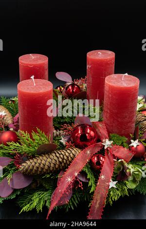 Vertikale, niedrige Ansicht des schönen neuen Adventskranzes mit vier roten Kerzen auf schwarzem Hintergrund. Platz für Text kopieren. Stockfoto