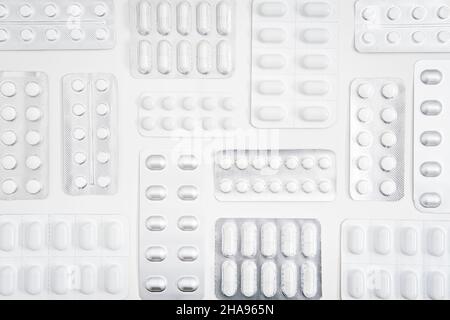 Weiße Pillen und Kapsel, Arzneitablette in Folienblisterverpackung mit weißem Hintergrund. Minimalistischer geometrischer medizinischer Hintergrund mit Vielfalt an Stockfoto