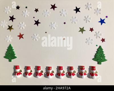 Winter themed flat lay, hölzerne Schneemänner, Glitzer Weihnachtsbäume, Sterne und Schneeflocken isoliert auf schlichtem Hintergrund mit Kopierraum Stockfoto