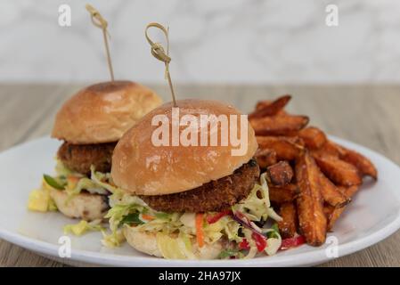 Künstlerische Präsentation von knusprig gebratenen Krabbenkuchen-Slidern auf Buttergebäck und serviert mit knusprigen pommes frites. Stockfoto