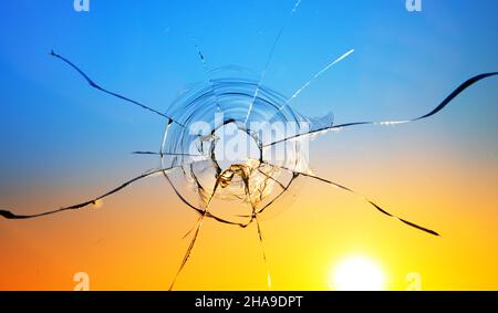 Kriegsbedrohungskonzept. Loch im Glas von einer Kugel auf dem Hintergrund der Flagge der Ukraine Stockfoto