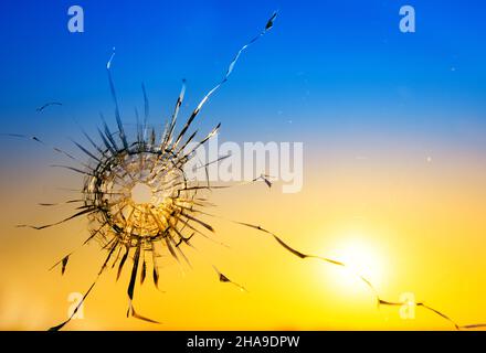 Kriegsbedrohungskonzept. Loch im Glas von einer Kugel auf dem Hintergrund der Flagge der Ukraine Stockfoto