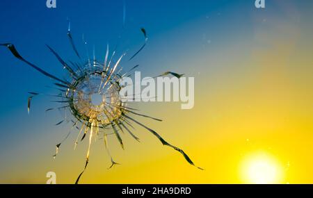 Kriegsbedrohungskonzept. Loch im Glas von einer Kugel auf dem Hintergrund der Flagge der Ukraine Stockfoto