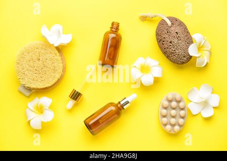 Badezubehör für Fußmassage und tropische Blumen auf gelbem Hintergrund Stockfoto