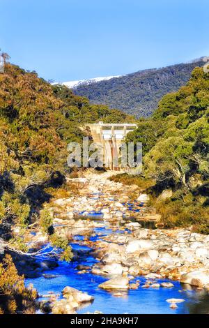 Grüner Energie-Wasserkraftdamm am Snowy River in den Snowy Mountains in Australien in der kalten Wintersaison, wenn die Berggipfel mit Schnee bedeckt sind. Stockfoto