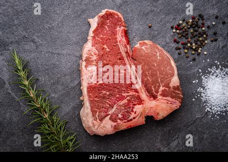 Rohes Porterhouse-Steak mit Rosmarin, gerissenem Pfeffer und koscheres Salz Stockfoto