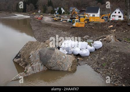 Konsul, Deutschland. 03rd Dez 2021. Trümmer von der historischen Bogenbrücke, die von der Flut weggefegt wurde, liegen in den Gewässern der Ahr, während Baumaschinen Grundstücke in der Nähe des Flussufers abbauen. Monate nach der Flutkatastrophe kämpfen die Menschen im Ahrtal noch immer mit den Folgen der Flut, viele Häuser mussten abgerissen werden, zahlreiche andere sind noch unbewohnbar. (Zu dpa-Bericht 'Advent im Ahrtal zwischen Hoffnung und Verzweiflung') Quelle: Boris Roessler/dpa/Alamy Live News Stockfoto