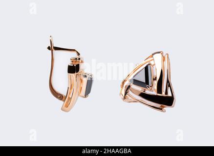 Goldene Ohrringe mit dem schwarzen Stein isoliert auf weißem Hintergrund Stockfoto
