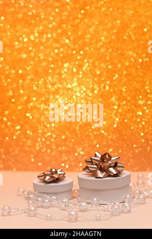 Zwei schöne Geschenkboxen auf einem glänzenden goldfarbenen Bokeh-Hintergrund. Stockfoto