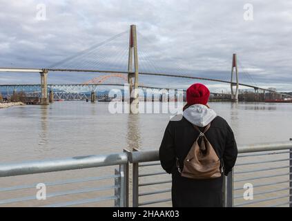 Die Skybridge ist eine Kabelbrücke für Skytrains zwischen New Westminster und Surrey. Eine Frau, die die Sky Bridge vom Westminster Pier Park aus betrachtet. S Stockfoto