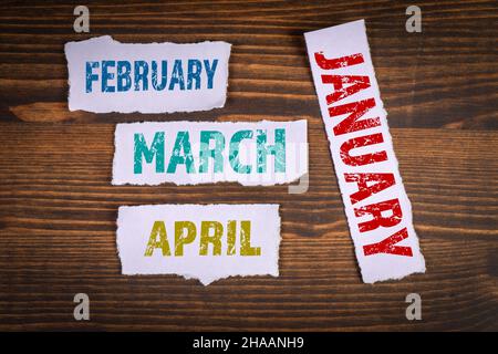 Januar Februar März und April. Zerrissenes Papier auf einem hölzernen Hintergrund. Stockfoto