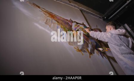 Künstler Designer zieht ein Adler an der Wand. Handwerker Dekorateur malt mit Acryl öl Farbe. Maler Maler gekleidet in Lack auftragen. Indoor. Stockfoto