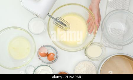 Frau mischt Eigelb und Zucker in einer Glasschüssel. Nahaufnahme Backvorgang, flach legen Stockfoto