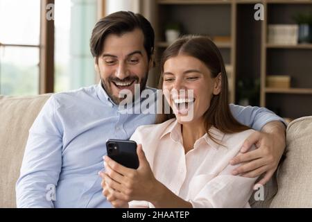 Glücklich aufgeregt junges Paar starrte auf Smartphone-Bildschirm Stockfoto