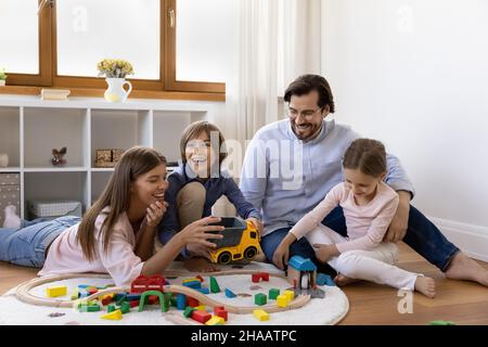 Glückliche Eltern und kleine Kinder spielen auf dem warmen Boden Stockfoto