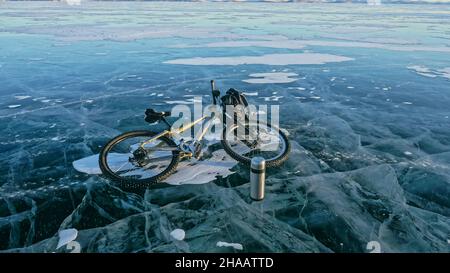 Mann und sein Fahrrad auf Eis. Er schaut auf das schöne Eis im Stockfoto