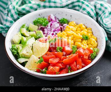 Salat mit Avocado, Tomaten, roten Zwiebeln und Mais in einer Schüssel. Vegetarische buddha-Schale. Vegane Küche. Stockfoto