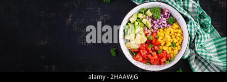 Salat mit Avocado, Tomaten, roten Zwiebeln und Mais in einer Schüssel. Vegetarische buddha-Schale. Vegane Küche. Draufsicht, Banner Stockfoto