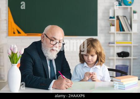 Reifer Großvater hilft Enkel mit Schulaufgabe, ältere Lehrer Ausbildung Schüler in der Lektion zu Hause, homeschooling Konzept. Stockfoto