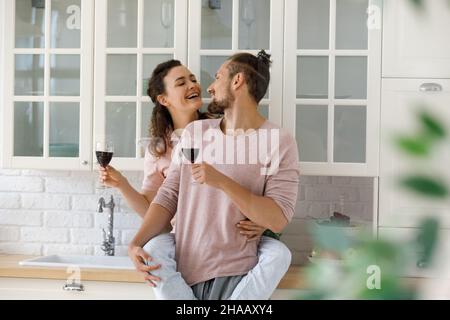 Fröhliche junge Dating-Paar Wein trinken, Spaß in der Küche Stockfoto