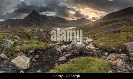 Episch dramatische Landschaftsaufnahme von Llyn Ogwen und Tryfan im Snowdonia National Park mit Bach und Felsen im Vordergrund Stockfoto