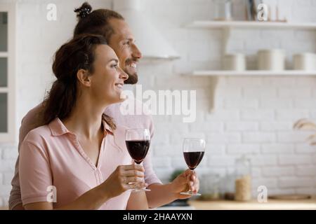 Fröhliches Paar, das Weingläser hält, in der Küche Rouge trinkt Stockfoto