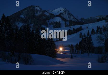 Bad Hindelang, Deutschland. 12th Dez 2021. Kurz vor Sonnenaufgang fährt ein Langlauffahrzeug auf der Loipe im Stadtteil Unterjoch. Quelle: Karl-Josef Hildenbrand/dpa/Alamy Live News Stockfoto