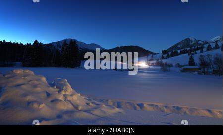 Bad Hindelang, Deutschland. 12th Dez 2021. Kurz vor Sonnenaufgang fährt ein Langlauffahrzeug auf der Loipe im Stadtteil Unterjoch. Quelle: Karl-Josef Hildenbrand/dpa/Alamy Live News Stockfoto