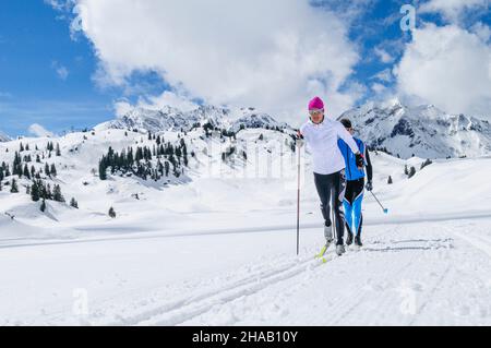 Zwei Langläufer laufen im klassischen Stil auf einer Höhenloipe in der Nähe des Hochtannbergpasses in Vorarlberg. Stockfoto