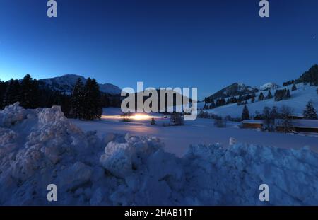 Bad Hindelang, Deutschland. 12th Dez 2021. Kurz vor Sonnenaufgang fährt ein Langlauffahrzeug auf der Loipe im Stadtteil Unterjoch. Quelle: Karl-Josef Hildenbrand/dpa/Alamy Live News Stockfoto