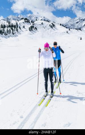 Zwei Langläufer laufen im klassischen Stil auf einer Höhenloipe in der Nähe des Hochtannbergpasses in Vorarlberg. Stockfoto